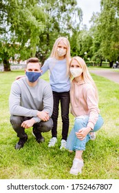 Family Members Embracing Each Other, Smiling In The Camera Wearing Cloth Face Masks. Father, Mother And Daughter Protect Themselves From The Virus.