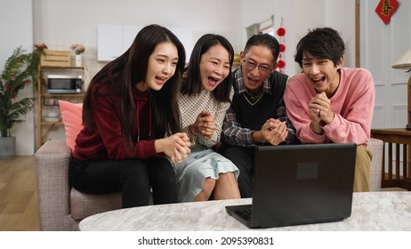 Family Members Waving Hands To Laptop Screen And Starting Talking Lively With Hand Gestures While Making Video Call To Friends On Chinese Lunar New Year At Home. Word On Door Translation: Spring