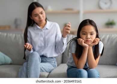 Family misunderstanding concept. Offended asian daughter sitting on couch, turning back to mother after quarrel at home, upset mom asking resentful girl what's wrong - Powered by Shutterstock