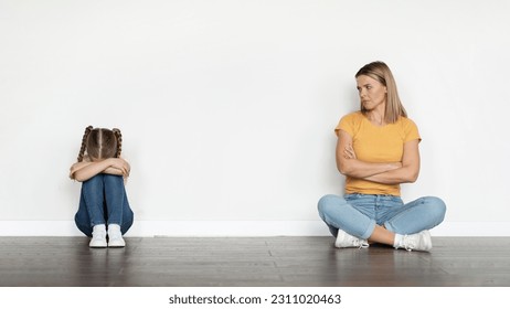 Family Misunderstanding Concept. Worried Young Mother Looking At Her Crying Offened Little Daughter After Argue At Home, Mom And Upset Female Child Sitting Apart On Floor Near White Wall, Copy Space - Shutterstock ID 2311020463