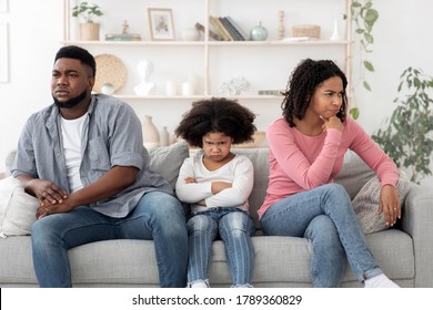 Family Misunderstanding. Offended Black Parents And Little Daughter Ignoring Each Other After Argue, Sitting With Grumpy Faces On Couch At Home