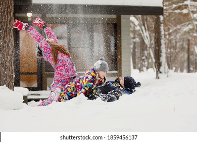 Family Mom, Dad And Daughter Have Fun And Play With Snow In The Winter Forest Near The House.