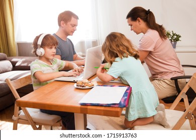 Family Mom, Dad And Two  Kids Sitting At The Table All Together. Children Learn Onlay From Home. Work From Home With Kids. Quarantin. Home Office.