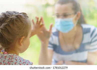 Family Mom And Daughter In Medical Mask.Young Happy Woman And Child Little Boy Sitting By The Window In Protective Masks Against The Virus. Baby Holding Hand On Glass. Mom Strokes The Baby's Face