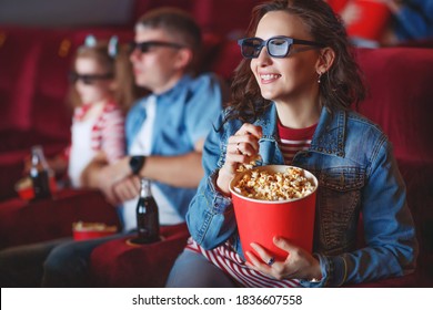 Family Mom Father And Children Are Watching A Projector, TV, Cinema, Movies With Popcorn In The Cinema. High Quality Photo.