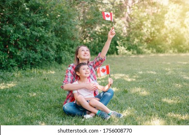 Family Mom With Son Celebrating National Canada Day On 1st Of July. Caucasian Mother With Child Boy Waving Canadian Flags. Proud Citizens Celebrate Canada Day In Park Outdoor. 