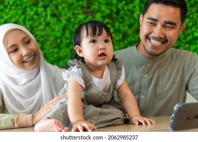 Family Moment: Young Malay Couple With Toddler At The Restaurant Smiling To Each Other