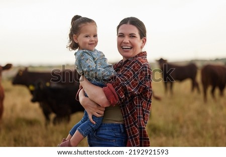 Family, mother and baby on a farm with cows in the background eating grass, sustainability and agriculture. Happy organic dairy farmer mom with her girl and cattle herd outside in sustainable nature