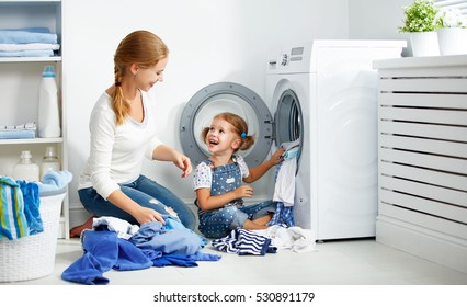 Family Mother And Child Girl Little Helper In Laundry Room Near Washing Machine And Dirty Clothes