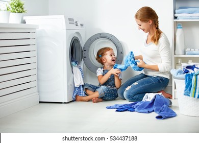 Family Mother And Child Girl Little Helper In Laundry Room Near Washing Machine And Dirty Clothes
