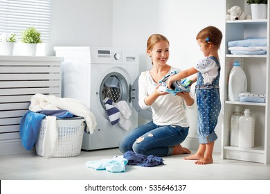 Family Mother And Child Girl Little Helper In Laundry Room Near Washing Machine And Dirty Clothes

