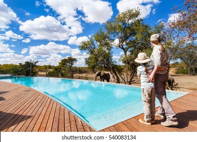 Family Of Mother And Child On African Safari Vacation Enjoying Wildlife Viewing Standing Near Swimming Pool