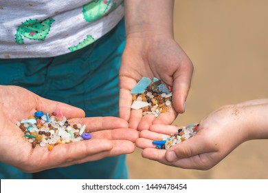 Family of mother and children holding and showing small tiny harmful plastic microbeads collected on the beach in Zante, Zakynthos, Greece