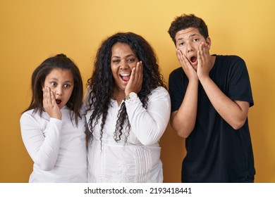 Family Of Mother, Daughter And Son Standing Over Yellow Background Afraid And Shocked, Surprise And Amazed Expression With Hands On Face 