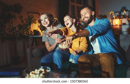 family mother father and child daughter watching projector, TV, movies with popcorn in the evening   at home 
