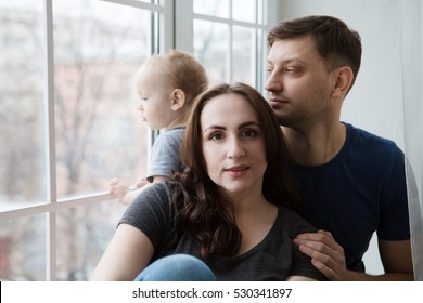 Family Mother, Father And Child Son  Look Out The Window On A Rainy Autumn Day
