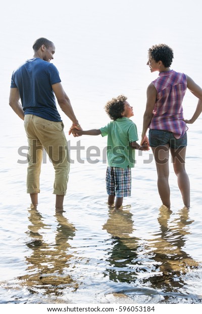 A family, mother, father and son playing on the\
shores of a lake