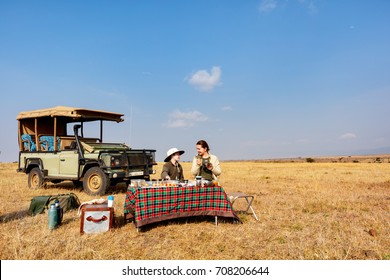 Family Of Mother And Her Son On African Safari Vacation Enjoying Bush Breakfast