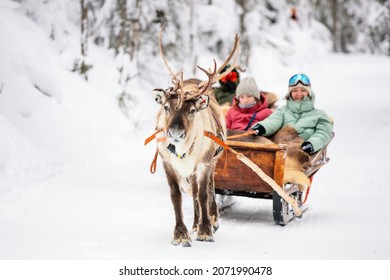Family mother and kids on reindeer safari in winter forest in Lapland Finland