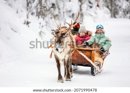 Family mother and kids on reindeer safari in winter forest in Lapland Finland
