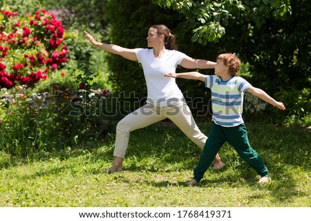 Family  mother and  son preschool child practice Tai Chi Chuan in a park.  Chinese management skill Qi's energy. solo outdoor activities. Social Distancing.  family exercising  together at the park. 
