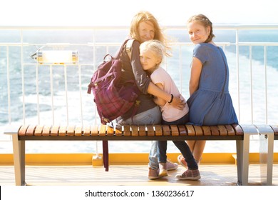 Family - Mother And Two Daughters Sitting On A Bench On The Ferry And The Sea In The Background
