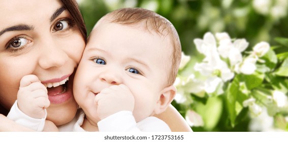 family and motherhood concept - happy smiling young mother with little baby over natural spring cherry blossom background