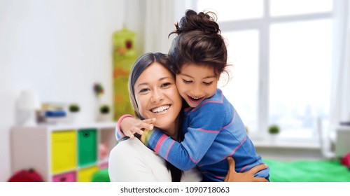 family, motherhood and people concept - happy mother and daughter hugging over over kids room at home background