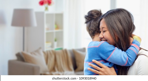 family, motherhood and people concept - happy mother and daughter hugging over over home room background