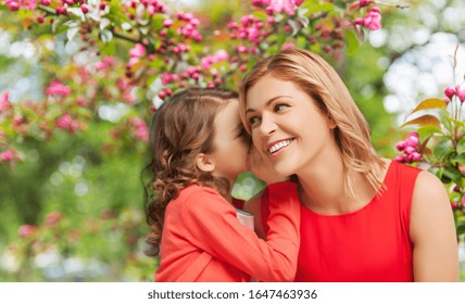 family, motherhood and people concept - happy smiling mother and daughter whispering her secret over cherry blossom background - Powered by Shutterstock