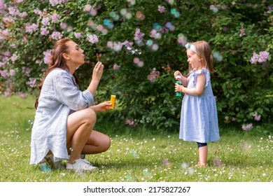 family, motherhood and people concept - happy mother with little daughter blowing soap bubbles at summer park or garden - Powered by Shutterstock