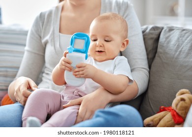 Family, Motherhood And People Concept - Mother And Little Baby Playing With Toy Phone At Home