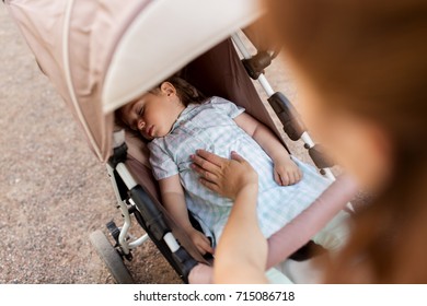 Family, Motherhood And People Concept - Mother With Child Sleeping In Stroller