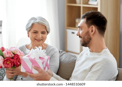 Family, Mother's Day And Birthday Concept - Smiling Adult Son Giving Present And Flowers To His Senior Mother At Home