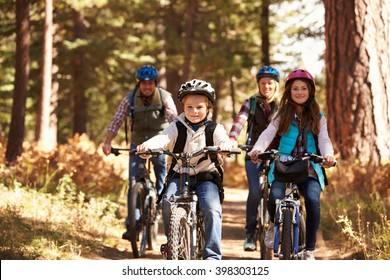 Family mountain biking on forest trail, front view
