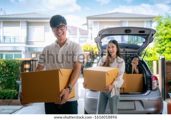Family Move house concept,\
asian father mother and daughter lift a paper box from old home to\
new home