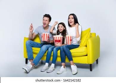 A Family Movie. Cheerful Family Of Mom, Dad And Little Child Are Watching Action Movies Together At Home, Eating Popcorn And Raising Hands While Shouting.