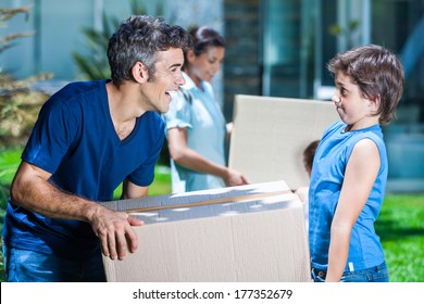 Family Moving Into A New House, Happy Parents With Two Children Carrying Box Smile