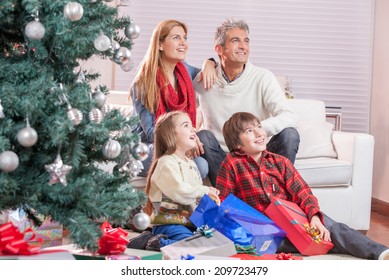 Family Near Chrismas Tree Awaiting Santa Claus Arrival.