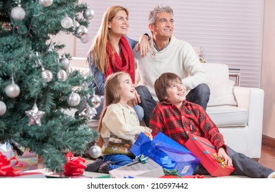 Family Near Chrismas Tree Awaiting Santa Claus Arrival.