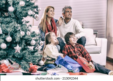 Family Near Chrismas Tree Awaiting Santa Claus Arrival.