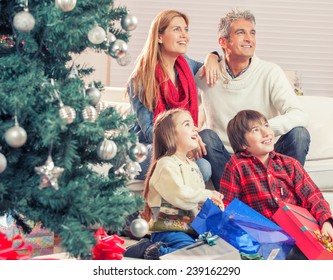 Family Near Chrismas Tree Awaiting Santa Claus Arrival.