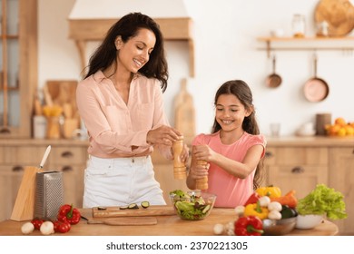 Family Nutrition. Happy Mother And Preteen Daughter Cooking And Seasoning Salad, Adding Salt And Pepper Spices To Food, Preparing Healthy Vegetable Meal For Dinner At Modern Kitchen Interior - Powered by Shutterstock