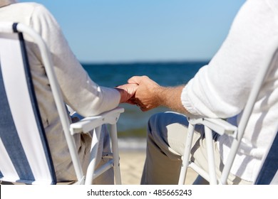 family, old age, travel, tourism and people concept - close up of happy senior couple sitting on deck chairs on summer beach
