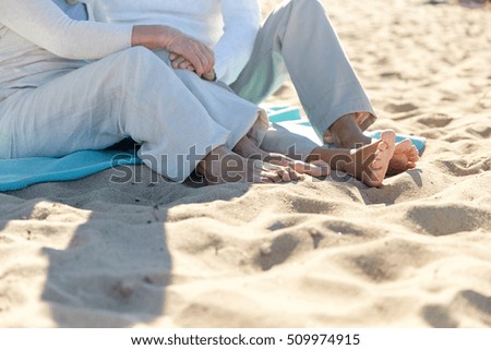 family, old age, travel, vacation and people concept - close up of happy senior couple sitting on plaid on summer beach