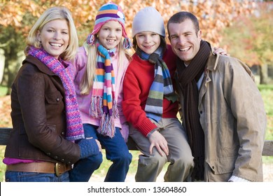 Family On Autumn Walk Sitting On Fence