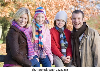 Family On Autumn Walk Sitting On Fence