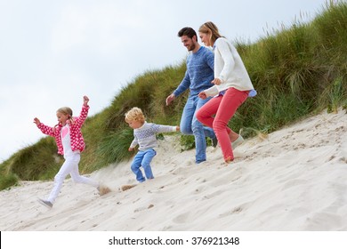 Family On Beach Vacation Running Through Dunes