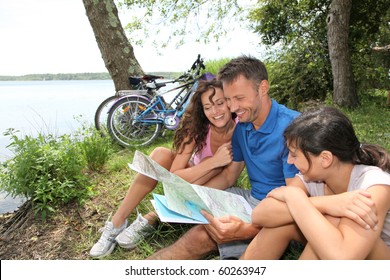 Family On A Bicycle Ride Looking At Map