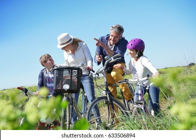 Family on a biking day making a stop and using smartphone